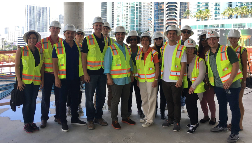 Group photo of students and professors wearing hard hats at a construction site.