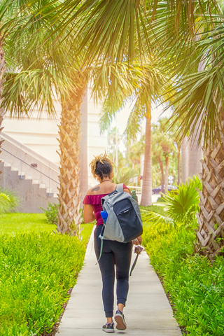 student walking on path under palm trees